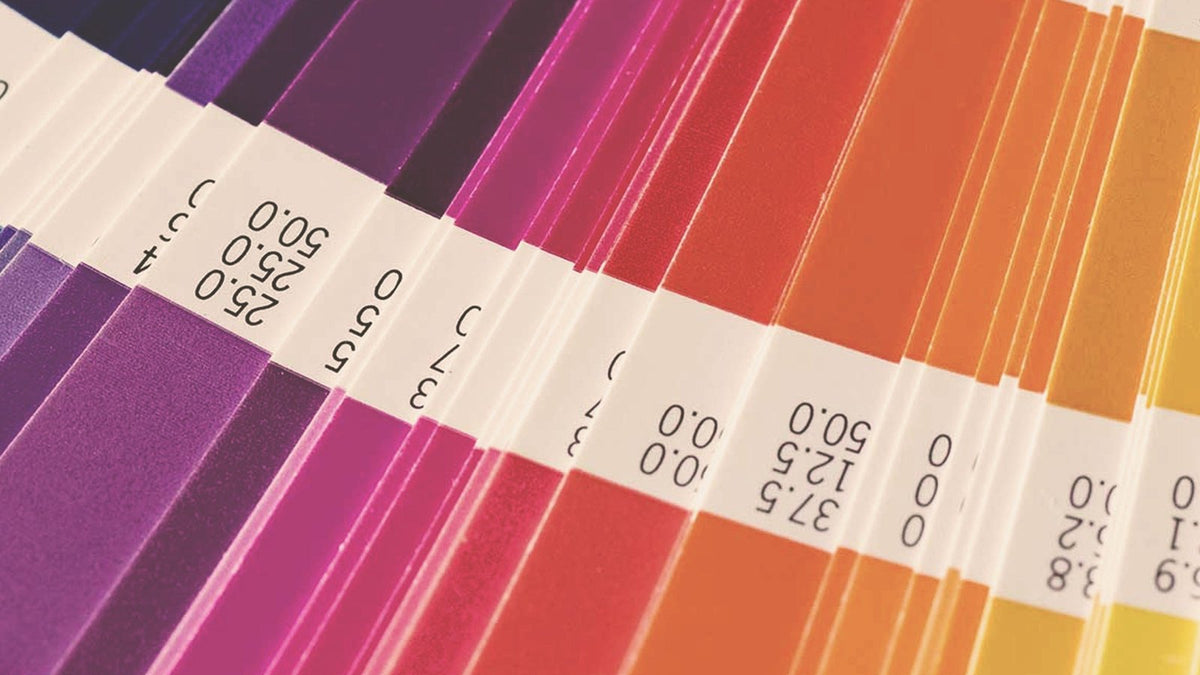 Close-up of a fanned Pantone color swatch guide with purple, magenta, orange and yellow chips