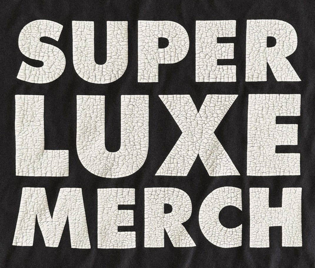 White crackle screen print reading Super Luxe Merch on a black tee