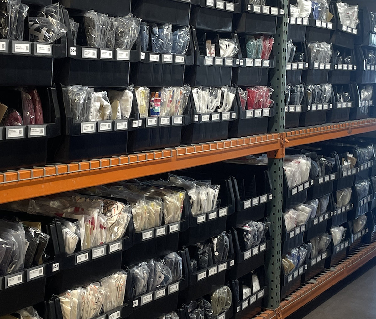 Bins of poly-bagged apparel on warehouse racking at Superluxe