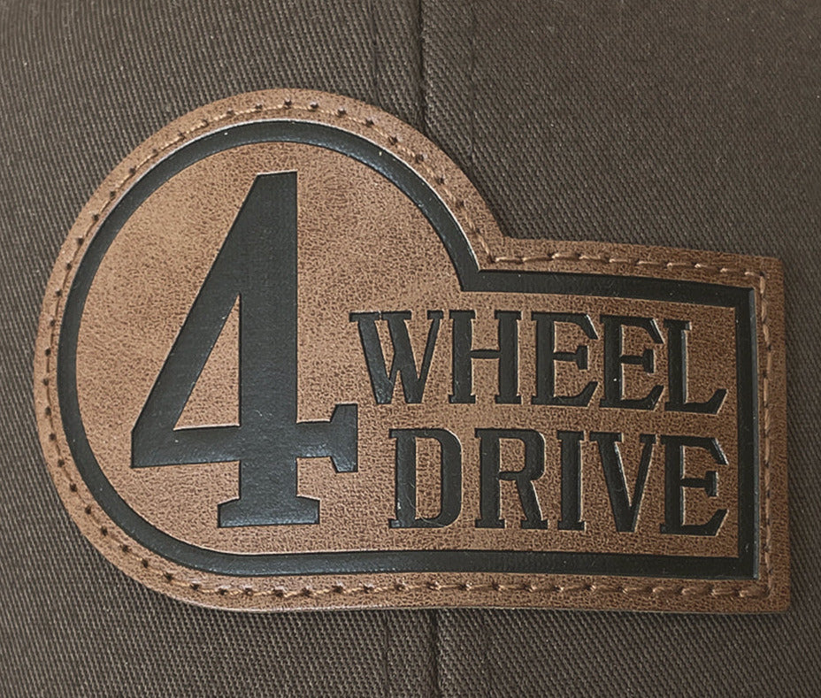 Close-up of a laser-engraved leatherette patch with faux top stitching on a brown trucker hat