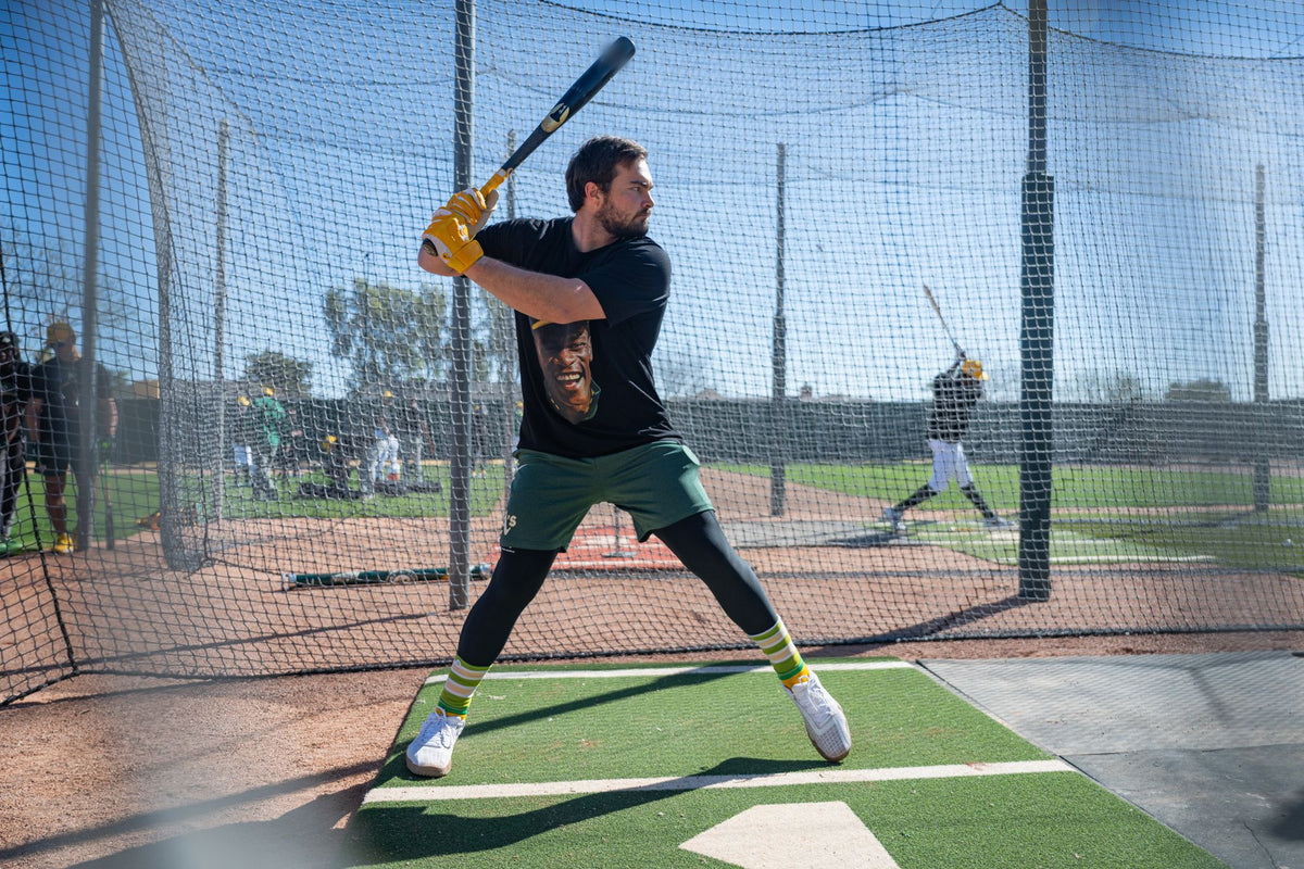 A player in the Rickey Henderson tribute tee in a batting stance in the batting cage