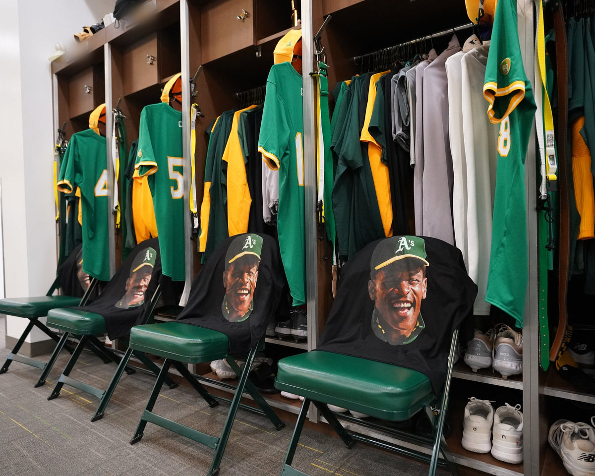 Rickey Henderson tribute tees draped over the chairs in front of the lockers in the A's clubhouse