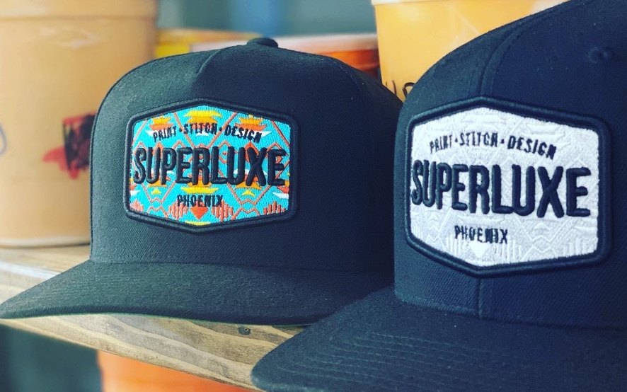 Two black Superluxe Phoenix patch caps on a shelf in our shop
