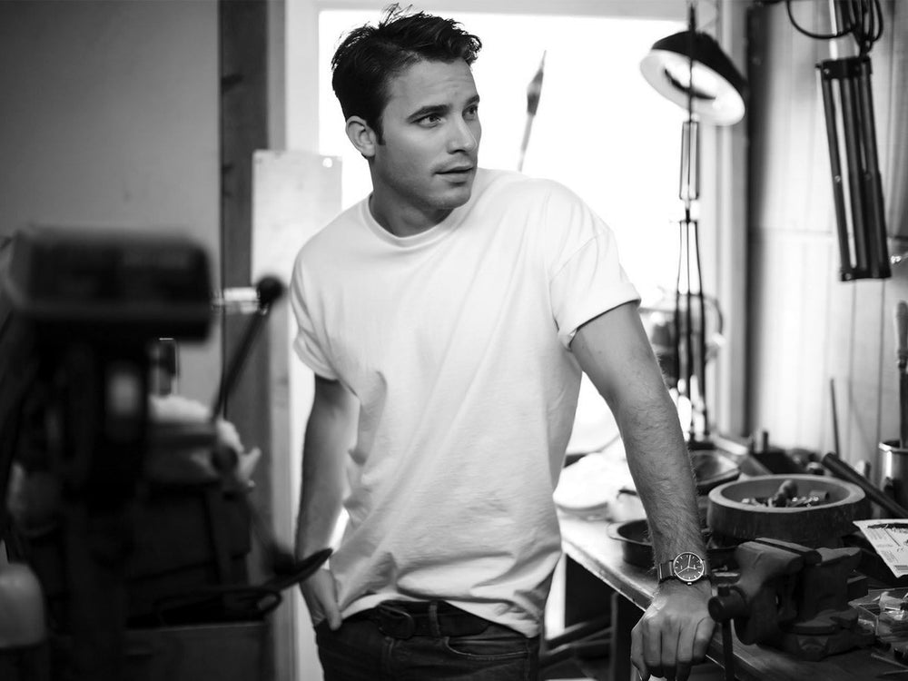 Man in a white heavyweight tee leaning on a workshop bench
