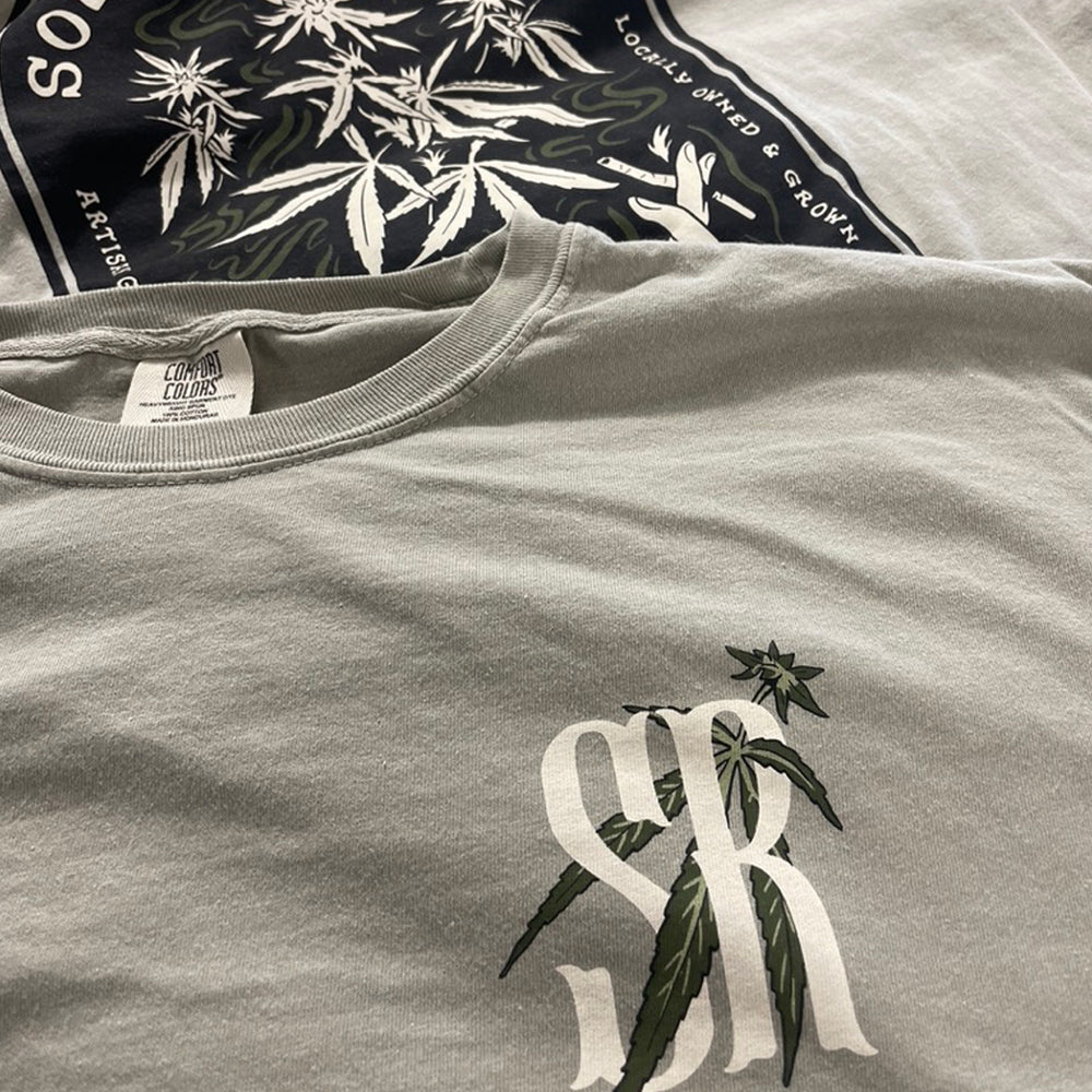 Stack of screen printed tees with soft-hand water-based prints, gray tee with a chest logo on top