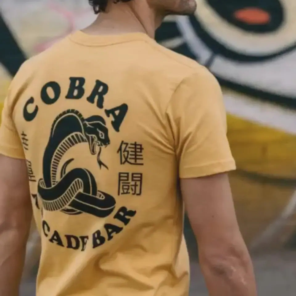 Man wearing a yellow Cobra Arcade Bar tee printed by Superluxe Merch